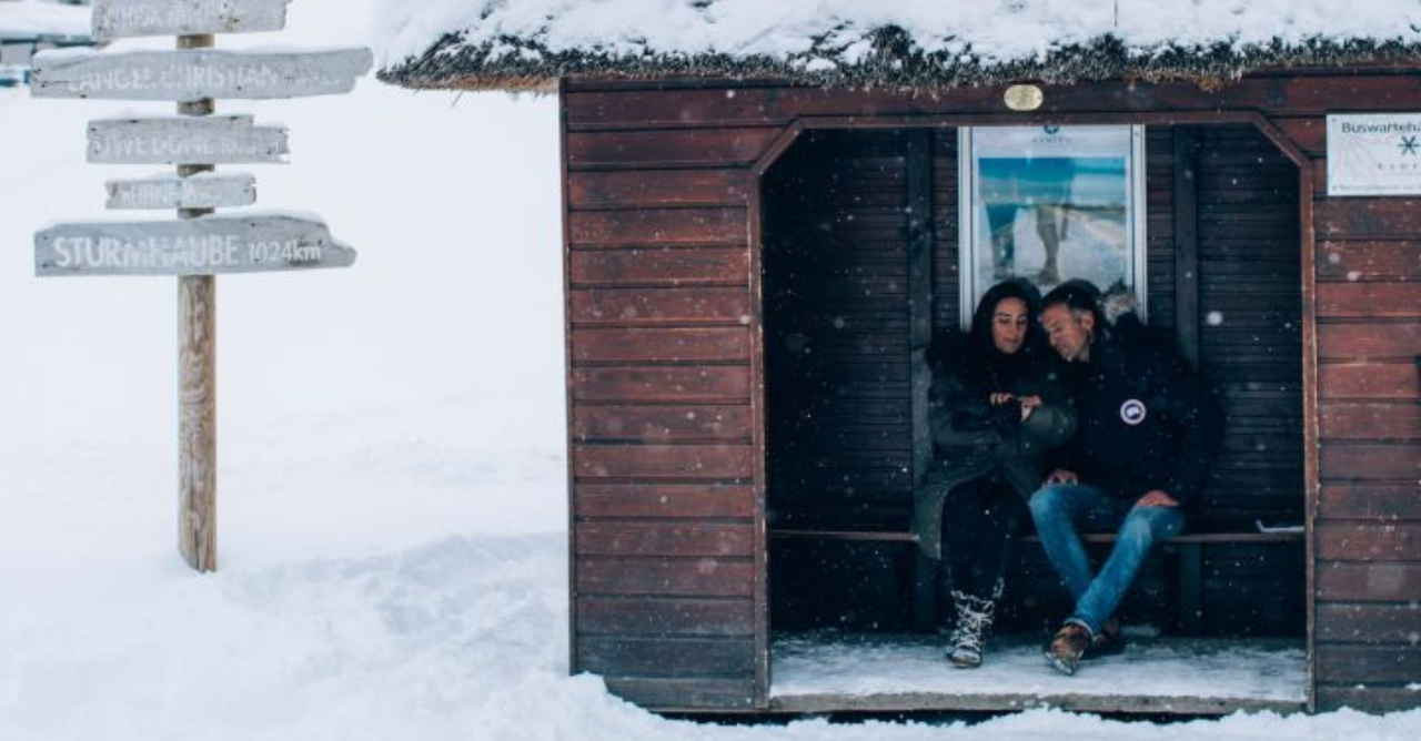 2 Personen an einer Haltestelle im Schnee