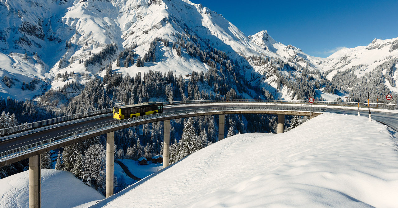 Ein Bus unterwegs in der verschneiten Winterlandschaft in den Bergen Vorarlbergs. 