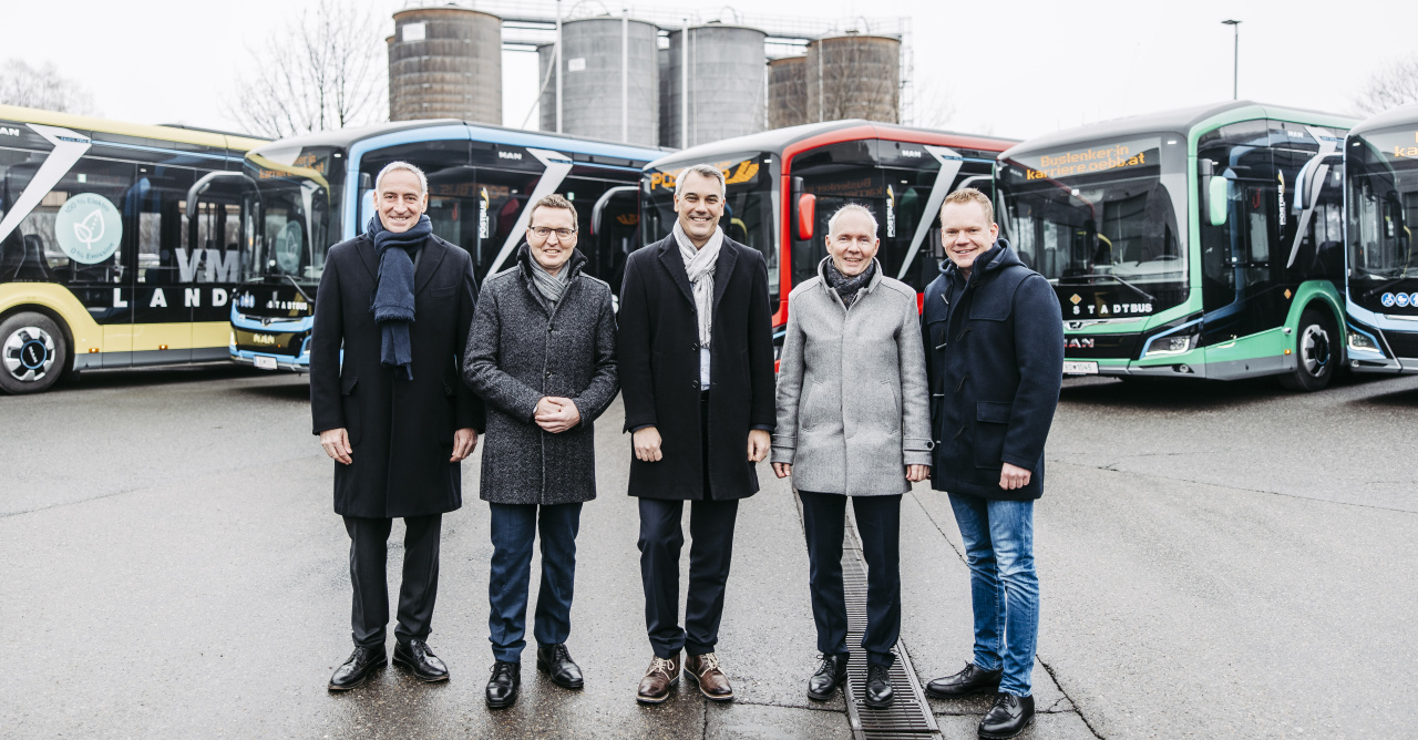 Bild vom Besuch bei ÖBB Postbus in Wolfurt mit Vertreter:innen von Politik und Partnern vor der bunten E-Busflotte