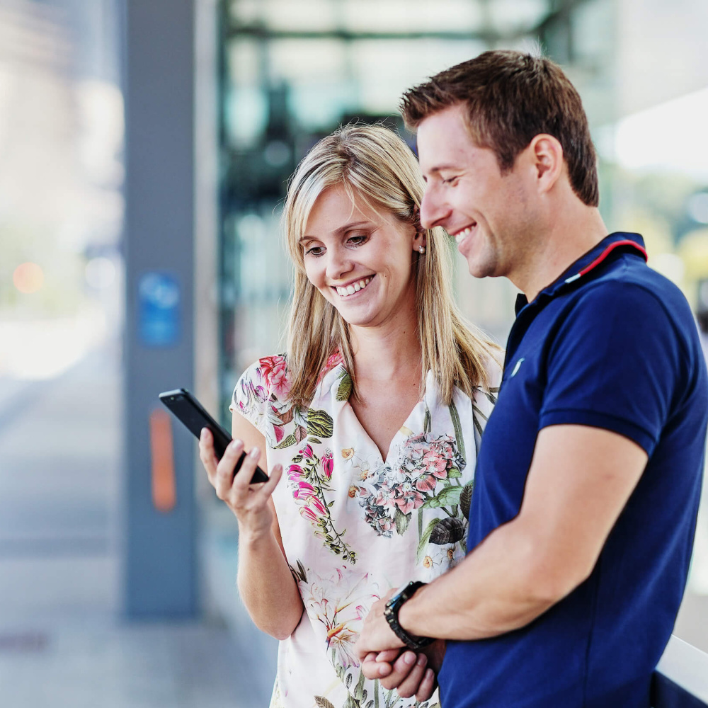 Mann und Frau am Busplatz mit Handy
