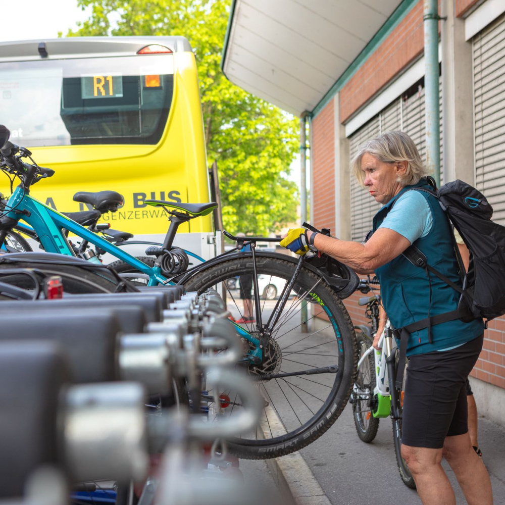 Eine Frau lädt ihr Fahrrad auf den Anhänger am Bus