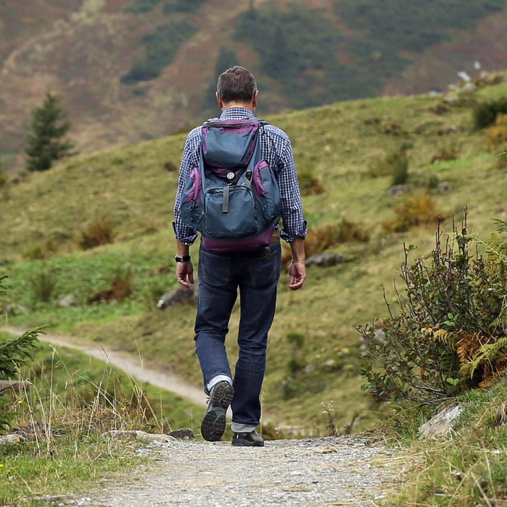 Ein Mann mit Rucksack auf einem Wanderweg im Gebirge