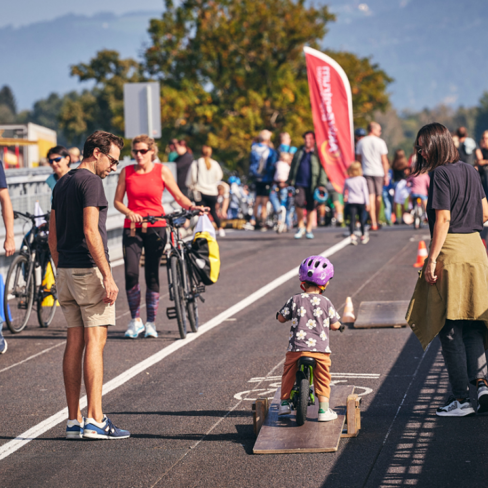 Kinder drehen bei einem Fahrradparcours beim Rad-Ried-Tag auf der gesperrten Senderbrücke ihre Runden. Erwachsene begleiten sie dabei. 