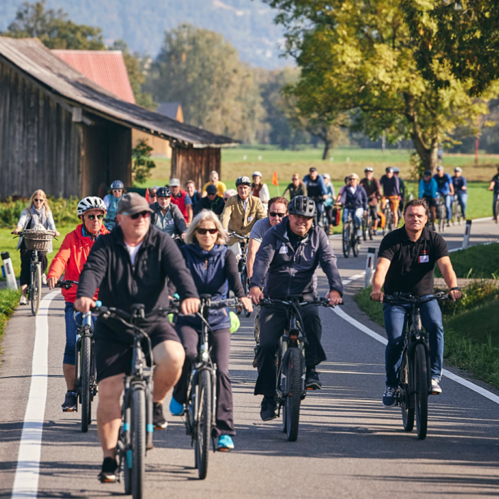 Menschen auf Fahrrädern auf der Straße im Ried gemeinsam auf dem Weg zum Festplatz des Rad-Ried-Tags