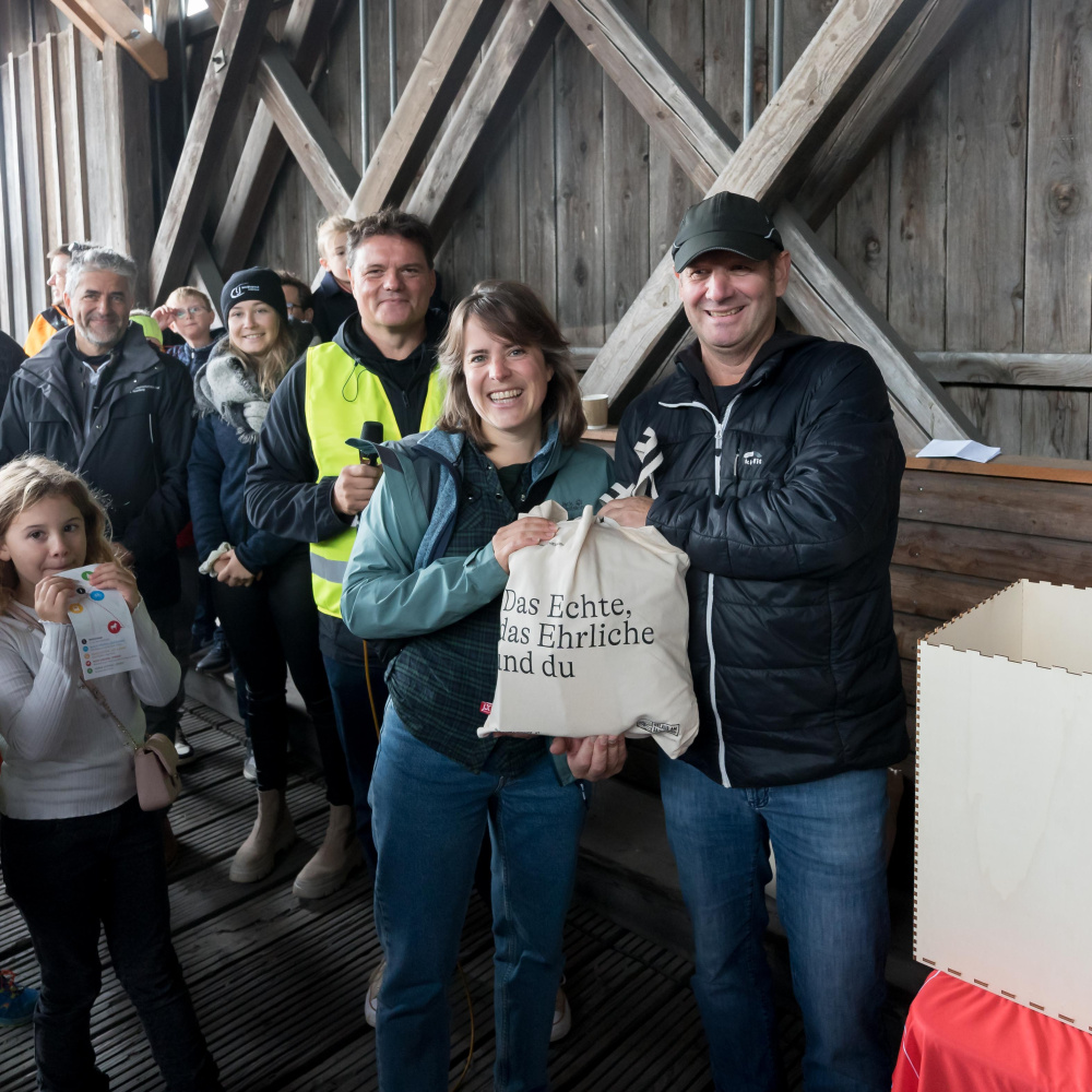 Vertreter der Landwirtschaftskammer Vorarlberg übergibt einer glücklichen Gewinnerin den Preis den Sie bei der Genussverlosung gewonnen hat
