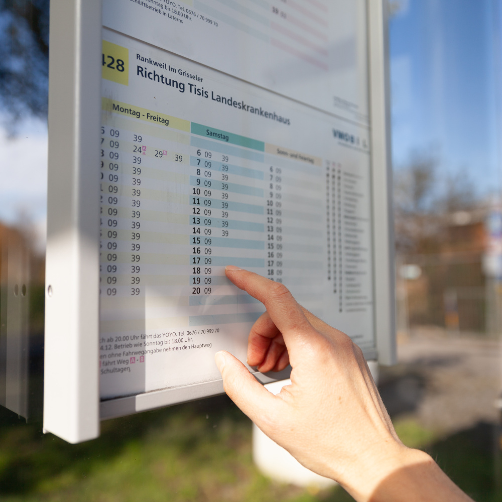 Fahrgast prüft die Fahrzeiten am Fahrplanaushangkasten an einer Haltestelle