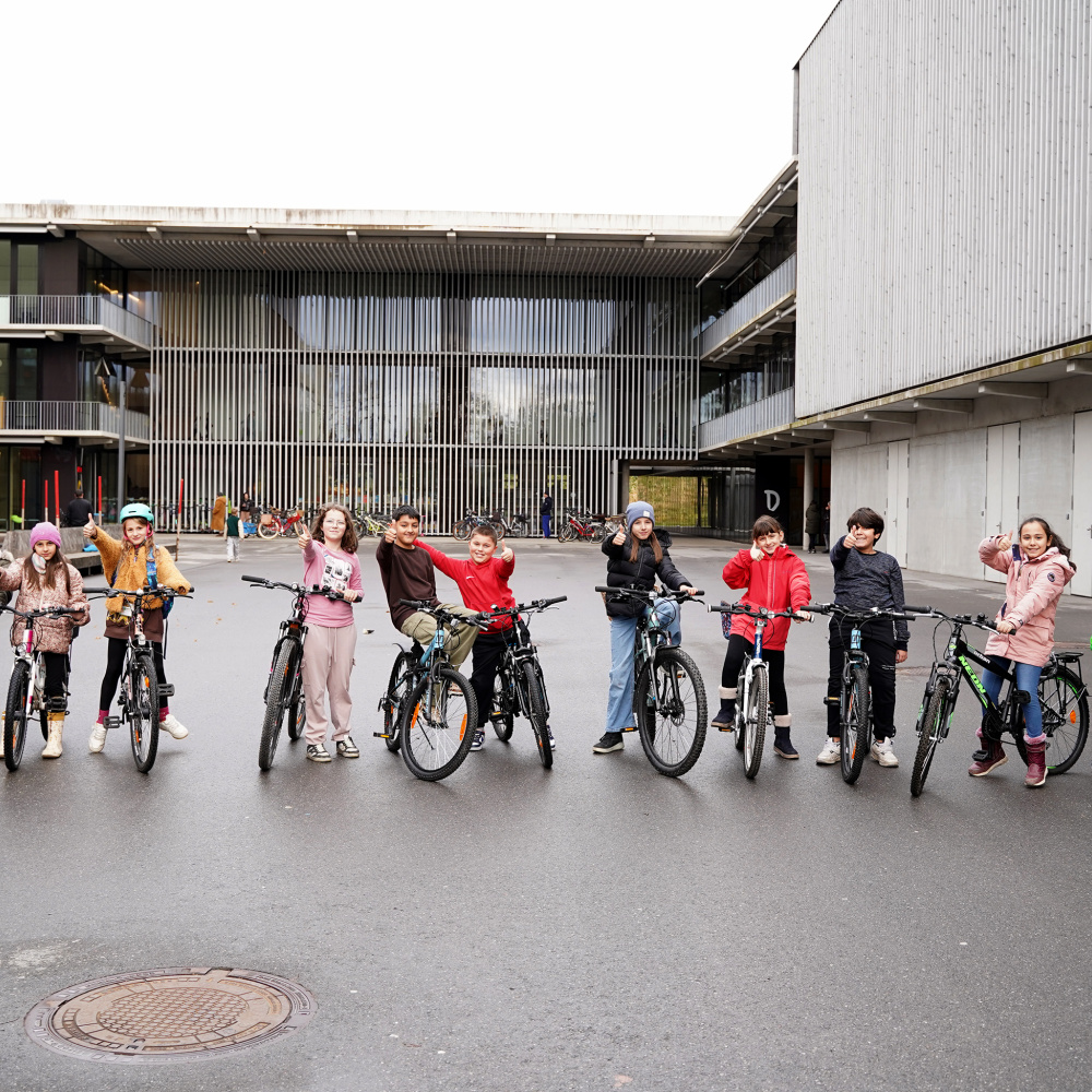 Volksschüler:innen stehen mit Ihrem Fahrrad vor dem Schulgebäude und freuen sich über den absolvierten Rad-Reparatur-Kurs