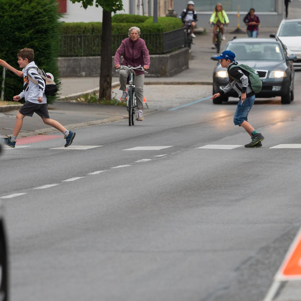 Schüler überqueren auf dem Weg zur Schule einen Zebrastreifen. Schülerlotsen sorgen für Sicherheit und stoppen die Autos.