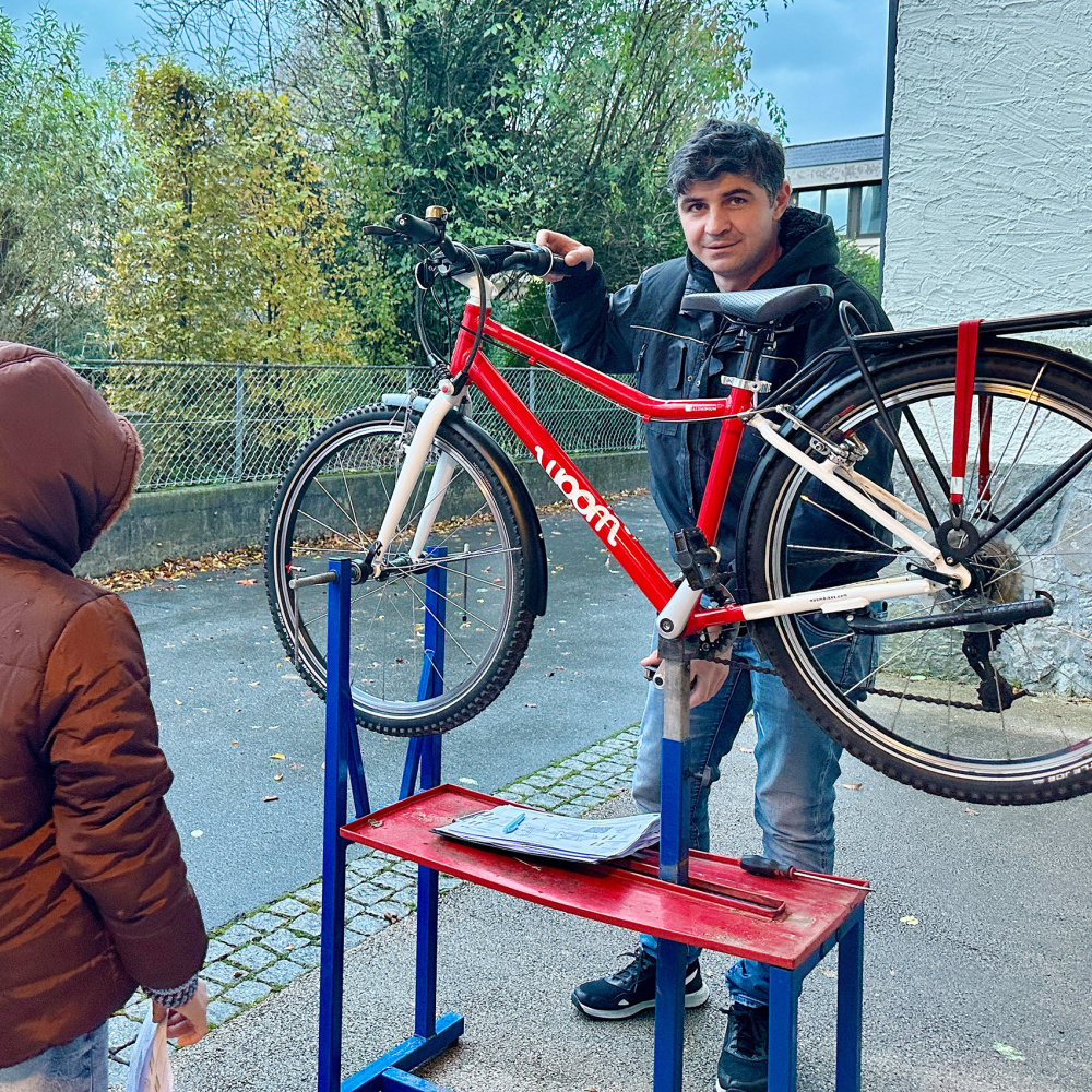 Kind und Mechaniker beim Rad-Reparatur-Kurs