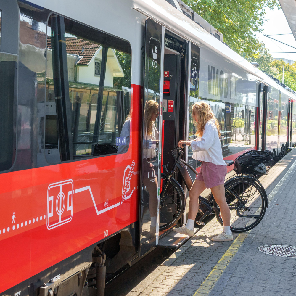 Frau mit Fahrrad zeigt in Nahverkehrszug ein