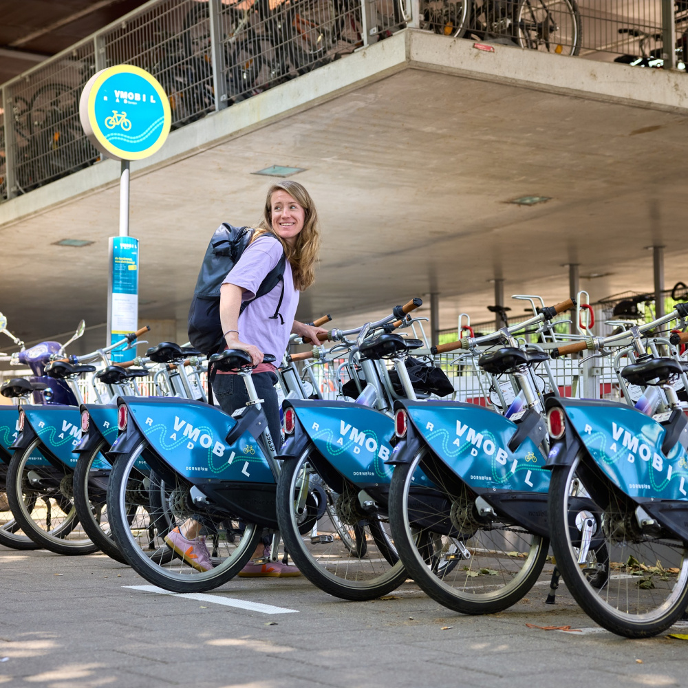 Frau mit VMOBIL Rad bei einer Leihradstation