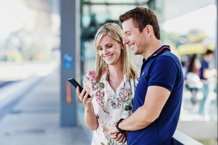 Mann und Frau am Busplatz mit Handy