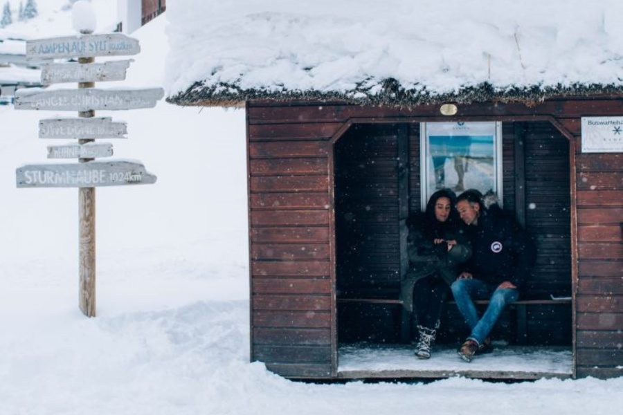2 Personen an einer Haltestelle im Schnee