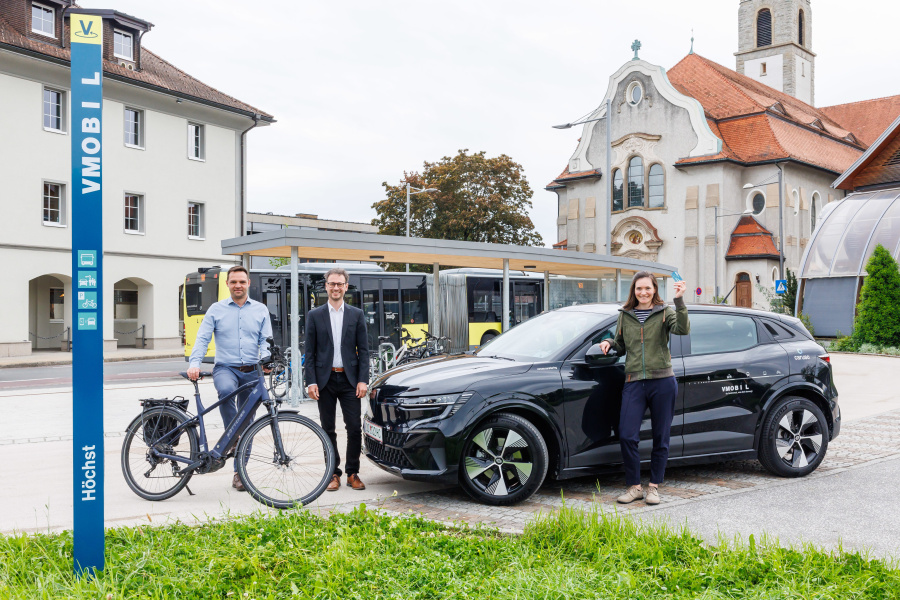 VMOBIL Station am Kirchplatz in Höchst mit Bürgermeister, Landesrat und Projektleiterin mit Bus, carsharing Auto und Rad im Bild