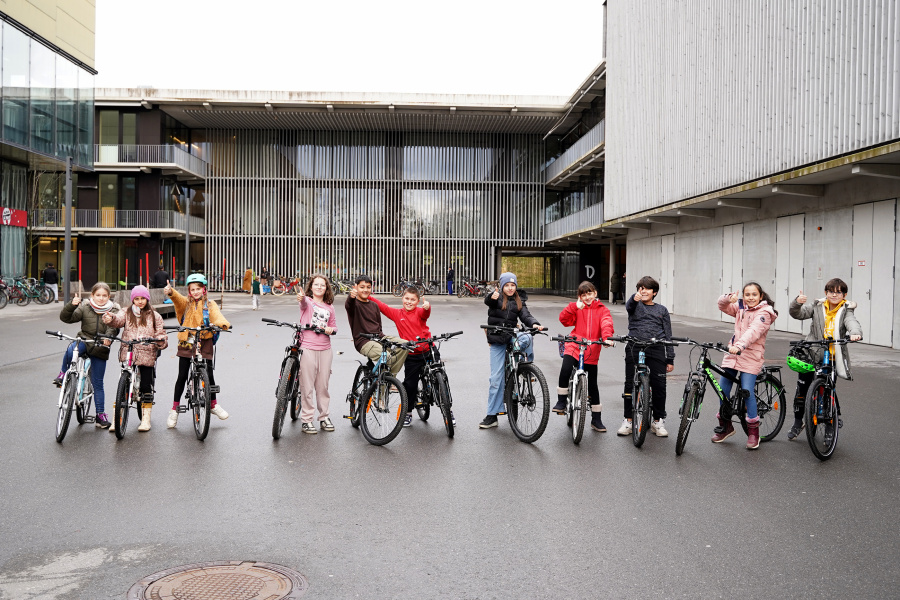 Volksschüler:innen stehen mit Ihrem Fahrrad vor dem Schulgebäude und freuen sich über den absolvierten Rad-Reparatur-Kurs