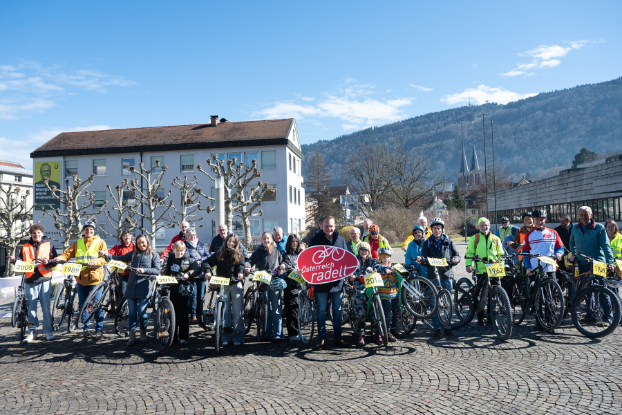 Zahlreiche Radfahrer:innen mit Jahrgangsnummern vor dem Landhaus. Landesstatthalter Christof Bitschi hält das Österreich radelt Schild.
