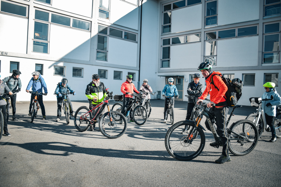 Teilnehmer:innen des Radpat:innen-Kurses stehen mit Ihrem Fahrrad beim asphaltierten Übungsplatz