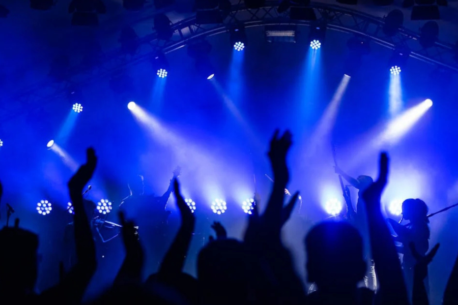 Konzert, Hände die Klatschen und im Hintergrund die leuchtende Bühne