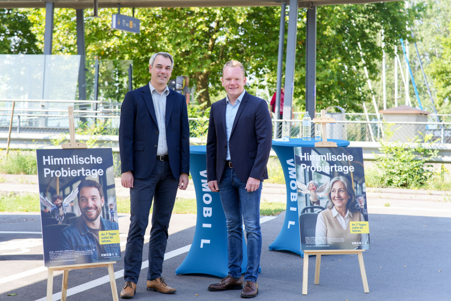 Verkehrsverbund Vorarlberg Geschäftsführer Christian Hillbrand und Landesstatthalter Christof Bitschi bei der Pressekonferenz mit den zwei Sujet-Tafeln zur VMOBIL-Woche "Himmlische Probiertage"
