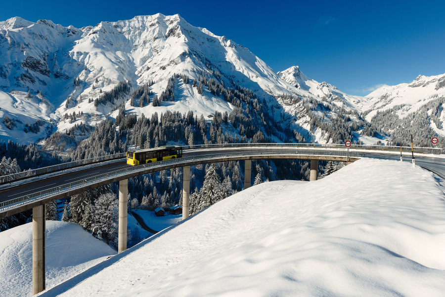 Ein Bus unterwegs in der verschneiten Winterlandschaft in den Bergen Vorarlbergs. 