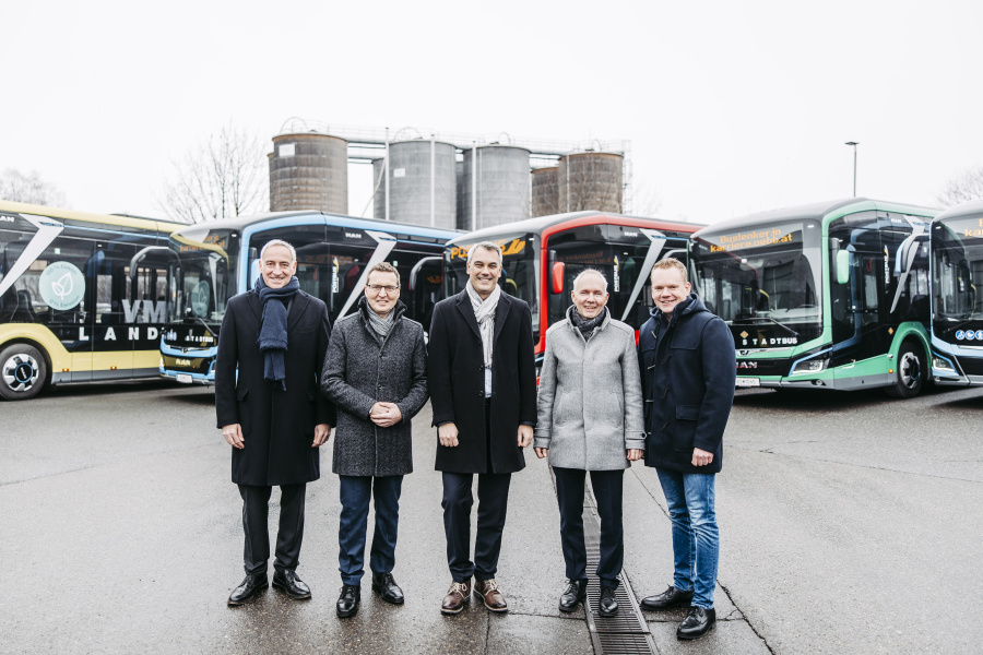Bild vom Besuch bei ÖBB Postbus in Wolfurt mit Vertreter:innen von Politik und Partnern vor der bunten E-Busflotte