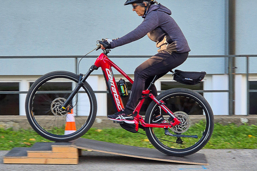 E-Bike-Fahrerin fährt beim Kurs über eine Rampe