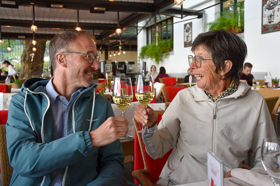 Eine Frau und ein Mann stoßen mit einem Gläschen Wein auf die Fahrrad-Genuss-Tour in einem Restaurant an. 