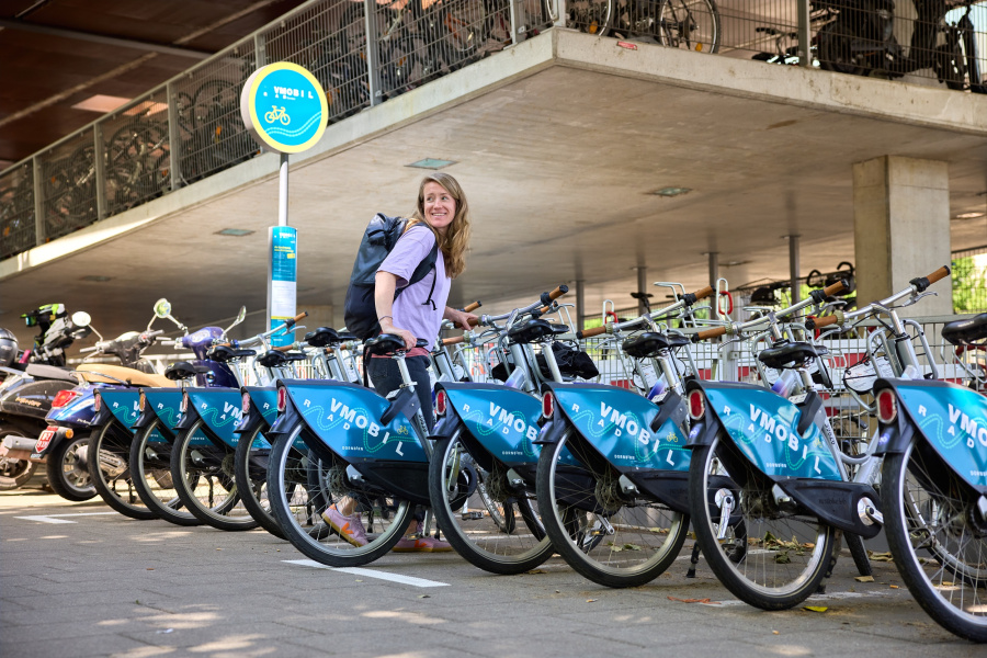 Frau mit VMOBIL Rad bei einer Leihradstation