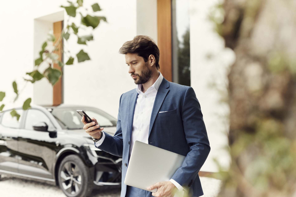 Mann bedient caruso carsharing App vor Carsharing-Auto.